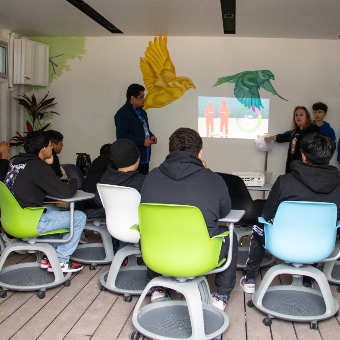 Students seated in a colourful technology classroom while instructors deliver a presentation