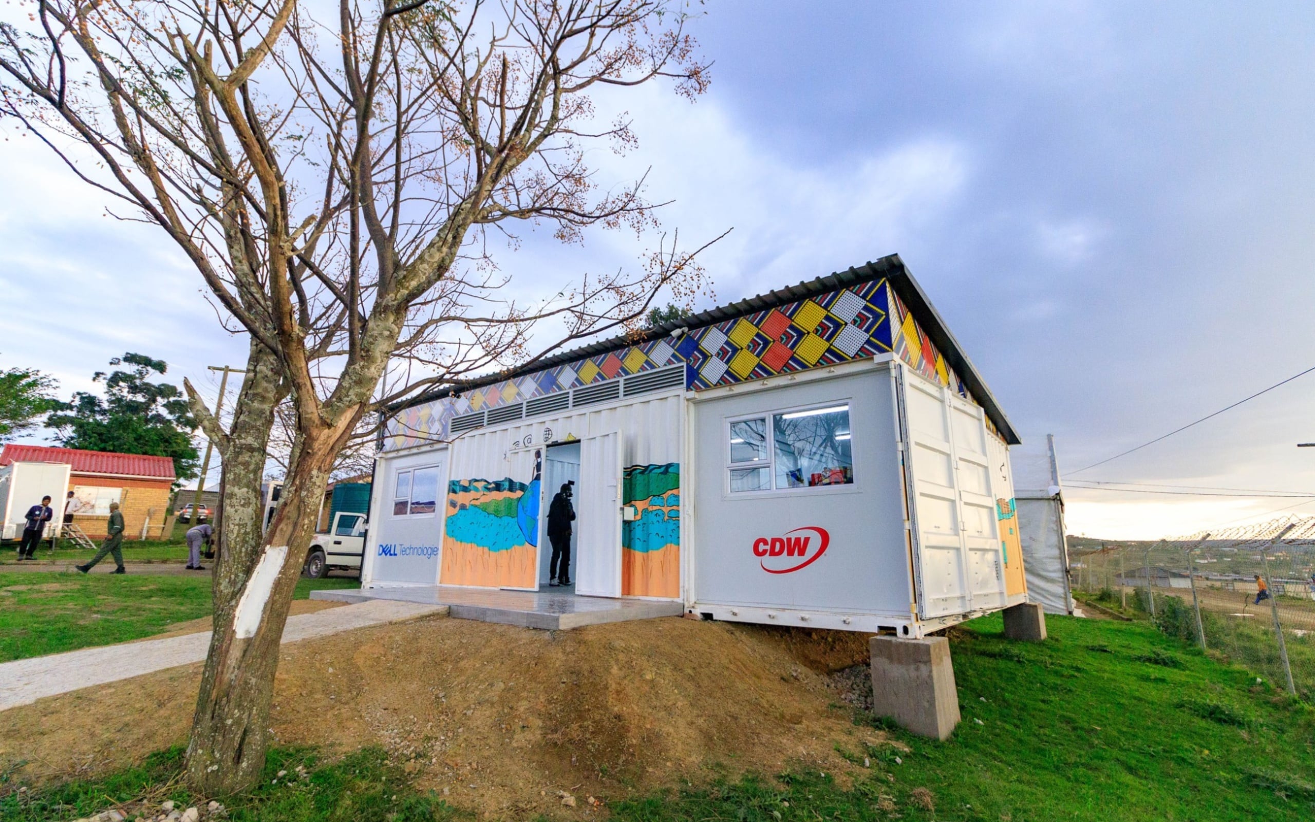 Colourful mobile technology classroom built from a converted shipping container beneath a large tree.