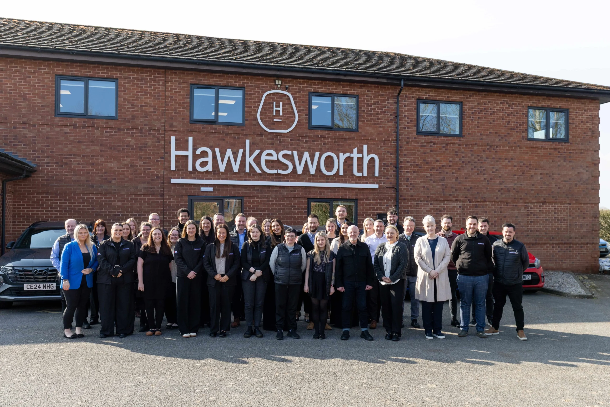 Hawkesworth team members standing together outside the company’s brick office building.